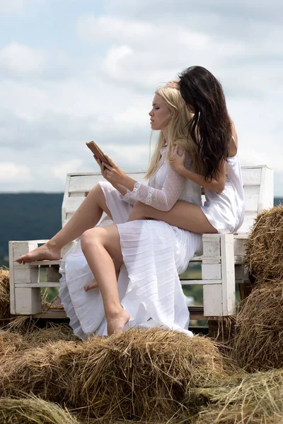 Meisjes boek lezen op houten bankje op hooi — Stockfoto