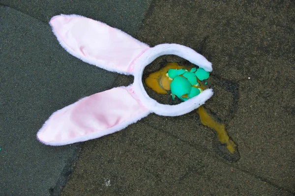 Easter egg broken and bunny ears headband on asphalt background Stock Image