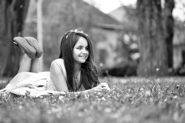 Petite fille sur herbe verte avec des pétales — Photo