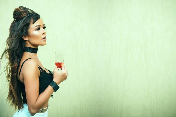 Girl holding glass of wine on beige wall