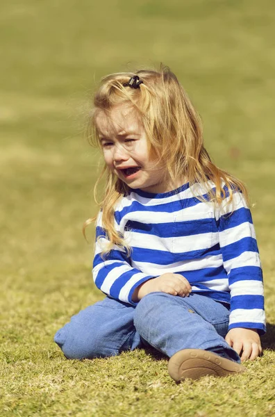 Infeliz lindo bebé niño sentado en verde hierba en parque —  Fotos de Stock