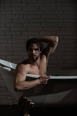 Küvet içinde oturan ıslak saçlı çocuk.