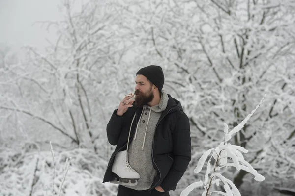 Sakallı adam tutun paten karlı kış orman, Noel, sigara içmek — Stok fotoğraf