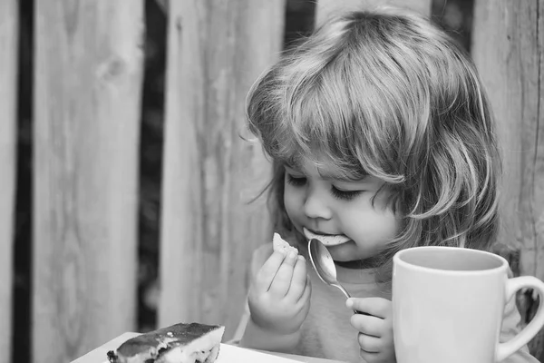 Liten pojke äta paj nära planket — Stockfoto