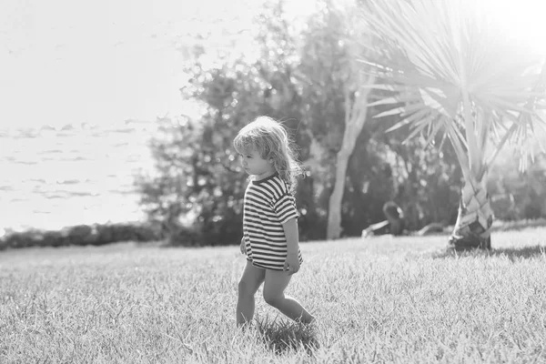 Şirin bebek çocuk çizgili tshirt yeşil çimenlerin üzerinde yürüyor — Stok fotoğraf
