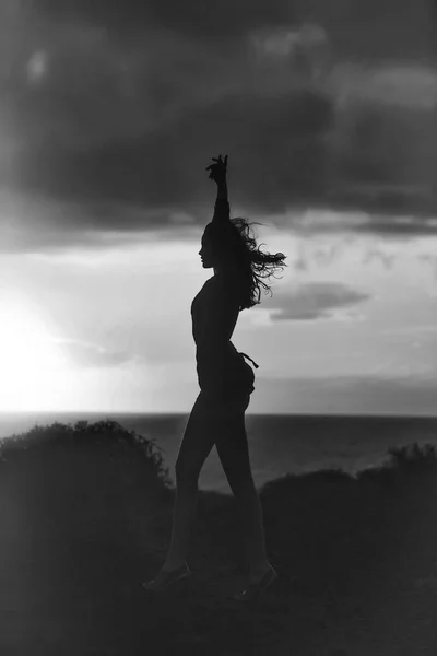 夕暮れ時の海のビーチできれいな女の子の黒いシルエット — ストック写真