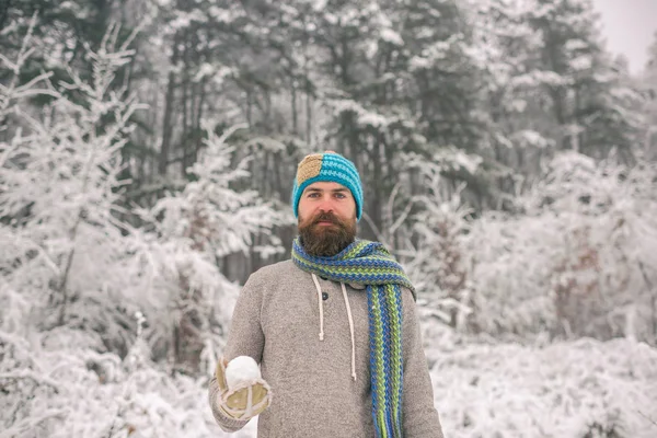 Vousatý muž s sněhová koule v zasněženém lese — Stock fotografie