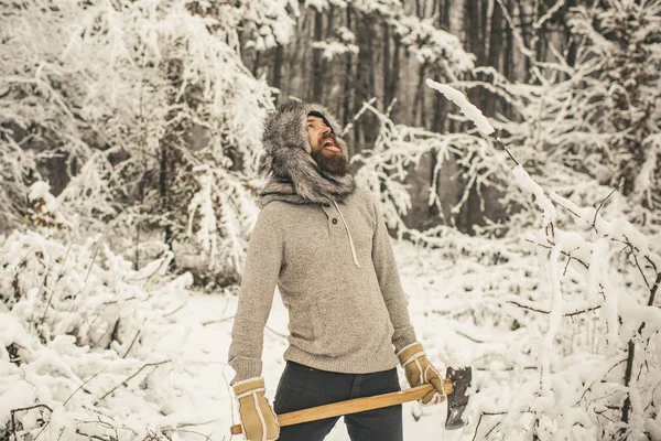 Homem barbudo lenhador segurar machado na floresta de inverno nevado, camping — Fotografia de Stock