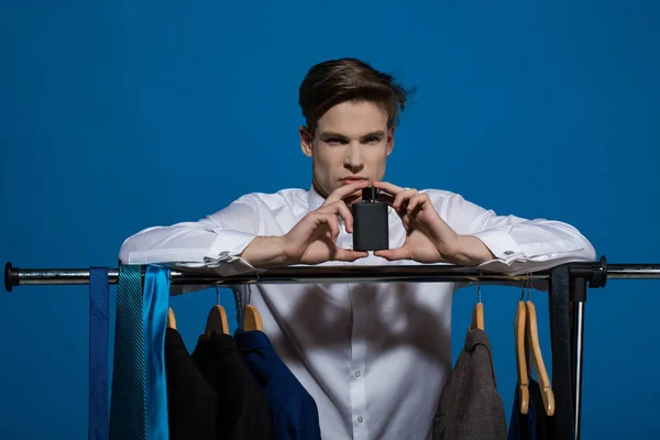 Mann hält Parfüm im Kleiderschrank auf blauem Hintergrund — Stockfoto