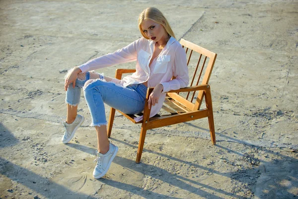 Sexy woman sit on wooden chair on concrete surface — Stock Photo, Image