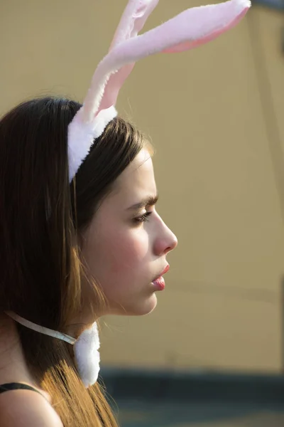 在米色背景上摆出轮廓的复活节妇女 女孩与弓和玫瑰色兔子耳朵在黑发头发 模型与健康的皮肤年轻的脸 健康和美容的概念 复活节节日庆典 — 图库照片