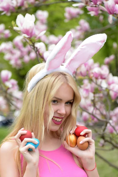 Pasen vrouw met eieren in bunny oren op magnolia, lente — Stockfoto