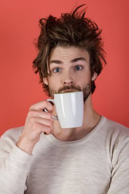 Çay bardağı kırmızı zemin üzerine şaşırmış adam. Uykusuzluk, ferahlık ve enerji. Dağınık saçlı adam mulled şarap iç. Sabah kahve veya süt ile. Soğuk algınlığı ve grip, tek.