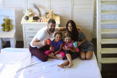 Anne, baba ve kızı evinde çay bardak ile. Neşeli ve mutlu aile kapalı yüzleri. Sevgi dolu aile ve rahat ev concept. Dostum, bir kadın ve şirin çocuk gülümseme ve renkli bardak tutun.