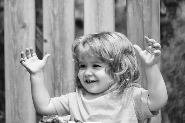 Маленький Мальчик Длинными Светлыми Волосами Смешным Лицом Сидит Деревянным Столом — стоковое фото