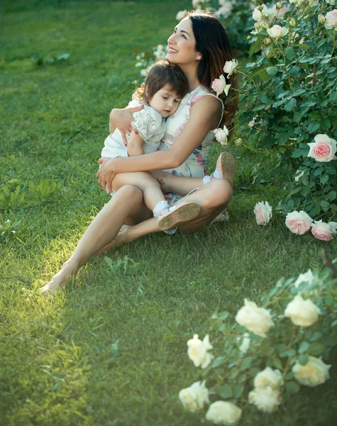 Woman smiling with baby girl on green grass — Stock Photo, Image