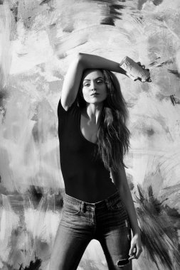 Uzun sarı saçlı kırmızı tshirt ve sprey boya şişe ile kot giyen kız ya da güzel ressam güzel veya pembe ve sarı soyut duvar grafiti için olabilir