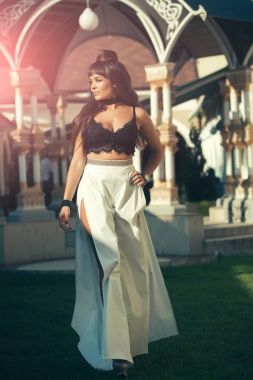 Glamour yaşam tarzı kavramı. Moda modeli kirletmek. Seksi elbiseyle yeşil çimenlerin üzerinde yürüyen kadın. Güzellik ve moda. Güneşli uzun esmer saç kızla.