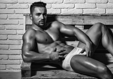 Yakışıklı adam veya kas maço, vücut geliştirmeci, seksi, kas gövde, altı paketleri ve sexi iç çamaşırı beyaz tuğla duvar arka koltukta ahşap palet üzerinde abs ile vücut ile