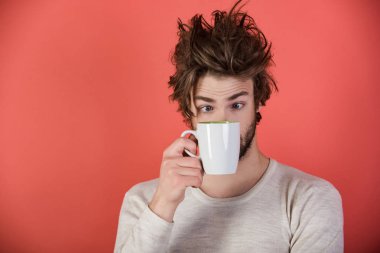 Sabah kahve veya süt ile. Çay bardağı kırmızı zemin üzerine şaşırmış adam. Soğuk algınlığı ve grip, tek. Dağınık saçlı adam mulled şarap iç. Uykusuzluk, ferahlık ve enerji.