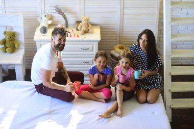 Anne, baba ve kızı evinde çay bardak ile. Sevgi dolu aile ve rahat ev concept. Dostum, bir kadın ve şirin çocuk gülümseme ve renkli bardak tutun. Neşeli ve mutlu aile kapalı yüzleri.