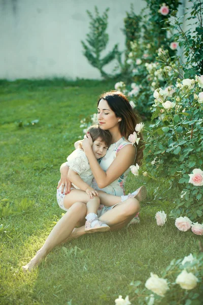 Mom and child relaxing at blossoming rose flowers — Stock Photo, Image