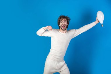 dağınık saçlı mutlu adam sabah mavi arka plan, enerji ve elektrik, güç ve iş başarı, çözüm fikir sembolü olarak büyük lamba tutun