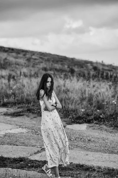 美丽的女孩苗条的女性模型与长黑发在夏天领域在自然背景的蓝色礼服 — 图库照片