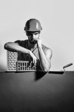 genç yakışıklı sakallı maço adam Oluşturucu seksi kaslı atletik güçlü vücut ile turuncu üniforma ve sabit hat ya da tuğla ve aracı, kopya alanı ile kask güçlü elinde vardır