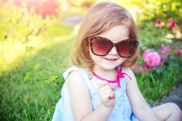 Menina Óculos Sol Sentado Parque Ambiente Floral Criança Sorrindo Com — Fotografia de Stock