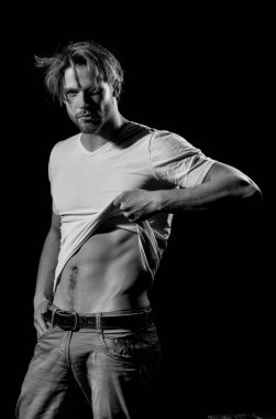 Yakışıklı adam veya tıraşsız maço, şık sarı saçlar, saç kesimi, beyaz tshirt gösteren seksi, kaslı vücut'la altı paketleri ve abs, pazı ile vücut geliştirmeci, triceps, striptiz siyah arka plan üzerine