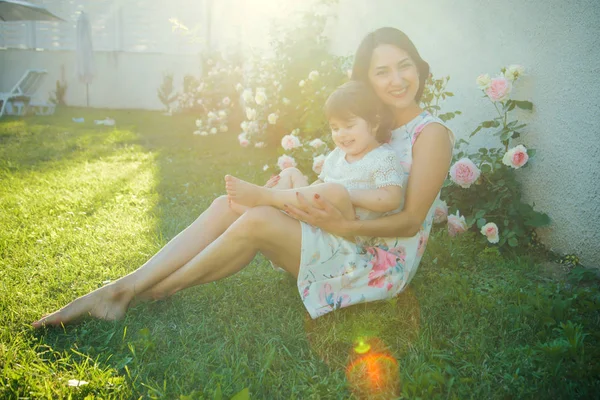 Mamá y el niño sonriendo al florecer flores de rosas —  Fotos de Stock