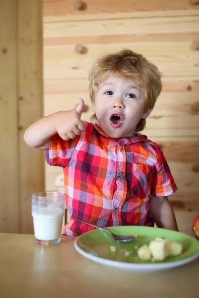 Kind of blonde gelukkige jongen eten aan tafel. — Stockfoto