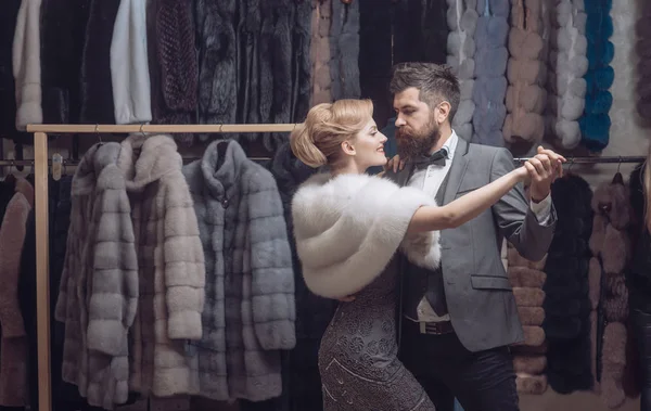 Man and woman with coats in fur shop.