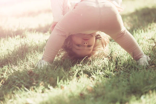 Fille debout sur la tête sur l'herbe verte le jour ensoleillé — Photo