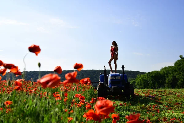 agronomist woman on tractor, poppy flower.