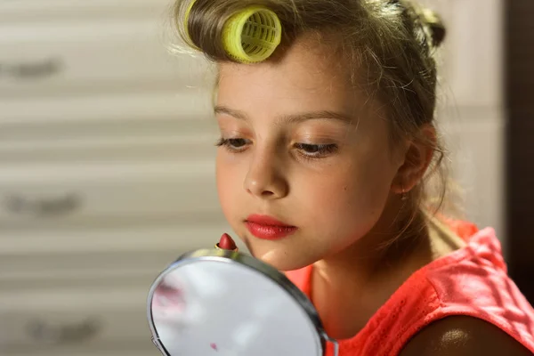 Kind met mooie wangen en ernstige gezicht schildert lippen binnenshuis — Stockfoto