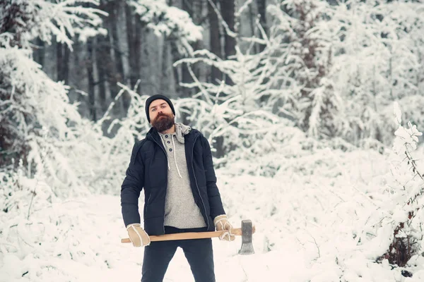 Homem barbudo lenhador segurar machado na floresta de inverno nevado, camping — Fotografia de Stock