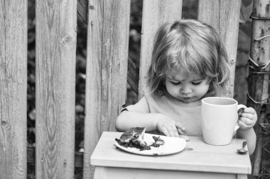 küçük çocuk ahşap çit yakınındaki pasta yemek