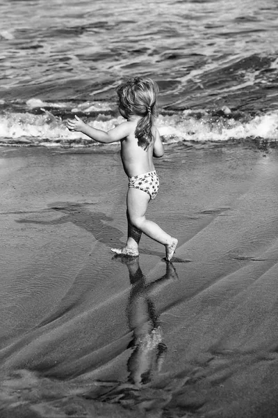 Lindo bebé alegre corre sobre arena mojada a lo largo del mar — Foto de Stock