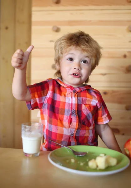 Kind of blonde gelukkige jongen eten aan tafel. — Stockfoto