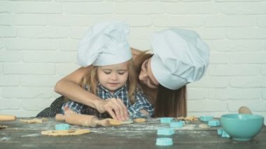 Mutlu aile birlikte fırın hazırlıyor. Anne ve kız çocuk kurabiye pişiriyor ve mutfakta eğleniyorlar. Ev yapımı yemek ve küçük bir yardımcı..
