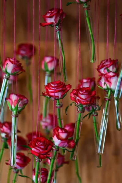 Bouteilles décorées avec des fleurs roses accrochées à la ficelle — Photo