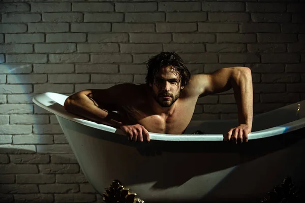 Sexy macho sentarse en la bañera en el baño — Foto de Stock