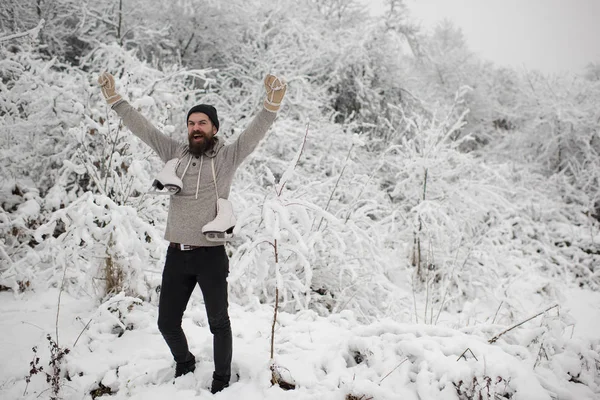 Bebaarde gelukkig man houden schaatsen in de winter van de besneeuwde bos, Kerstmis — Stockfoto