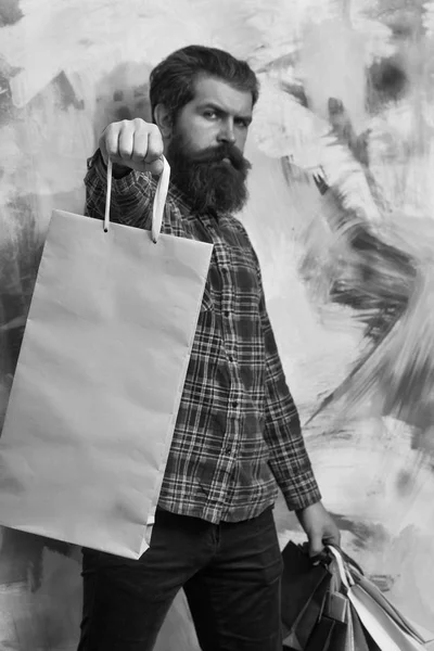 Ernstige bebaarde man met kleurrijke papieren draagtassen — Stockfoto