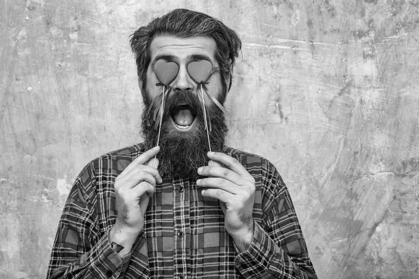 Happy bebaarde man met rode harten op stokjes voor ogen — Stockfoto