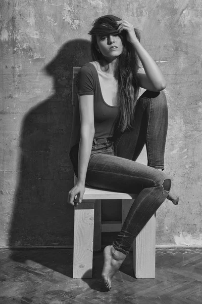 Menina bonita sentada na cadeira de madeira branca com pernas — Fotografia de Stock
