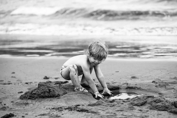 Söt leriga baby pojke leker med våt sand — Stockfoto