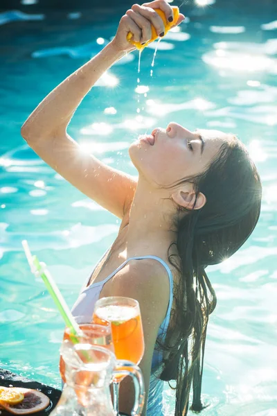 Mujer exprimir el jugo de la fruta de naranja en el bar de la piscina —  Fotos de Stock